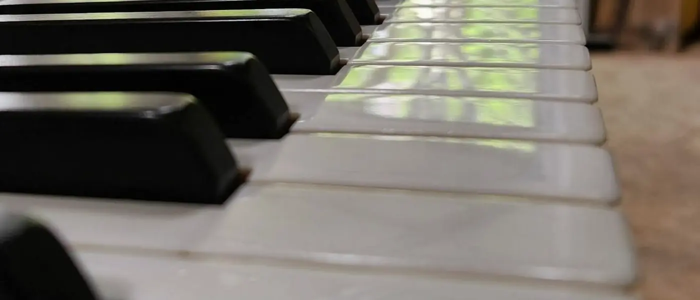 Clavier de piano démonté, posé sur un établi devant une fenêtre
