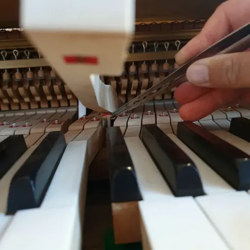 Intervention à la pince sur la mécanique d'un piano droit