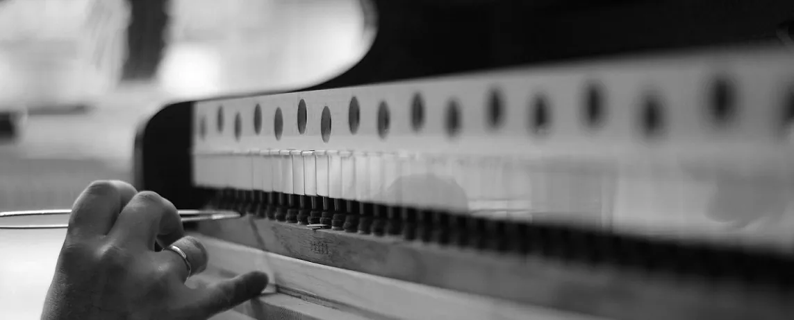 Main de l'accordeur réglant la mécanique d'un piano