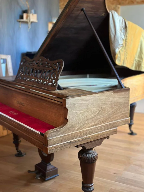 Piano à queue ancien au meuble en bois verni